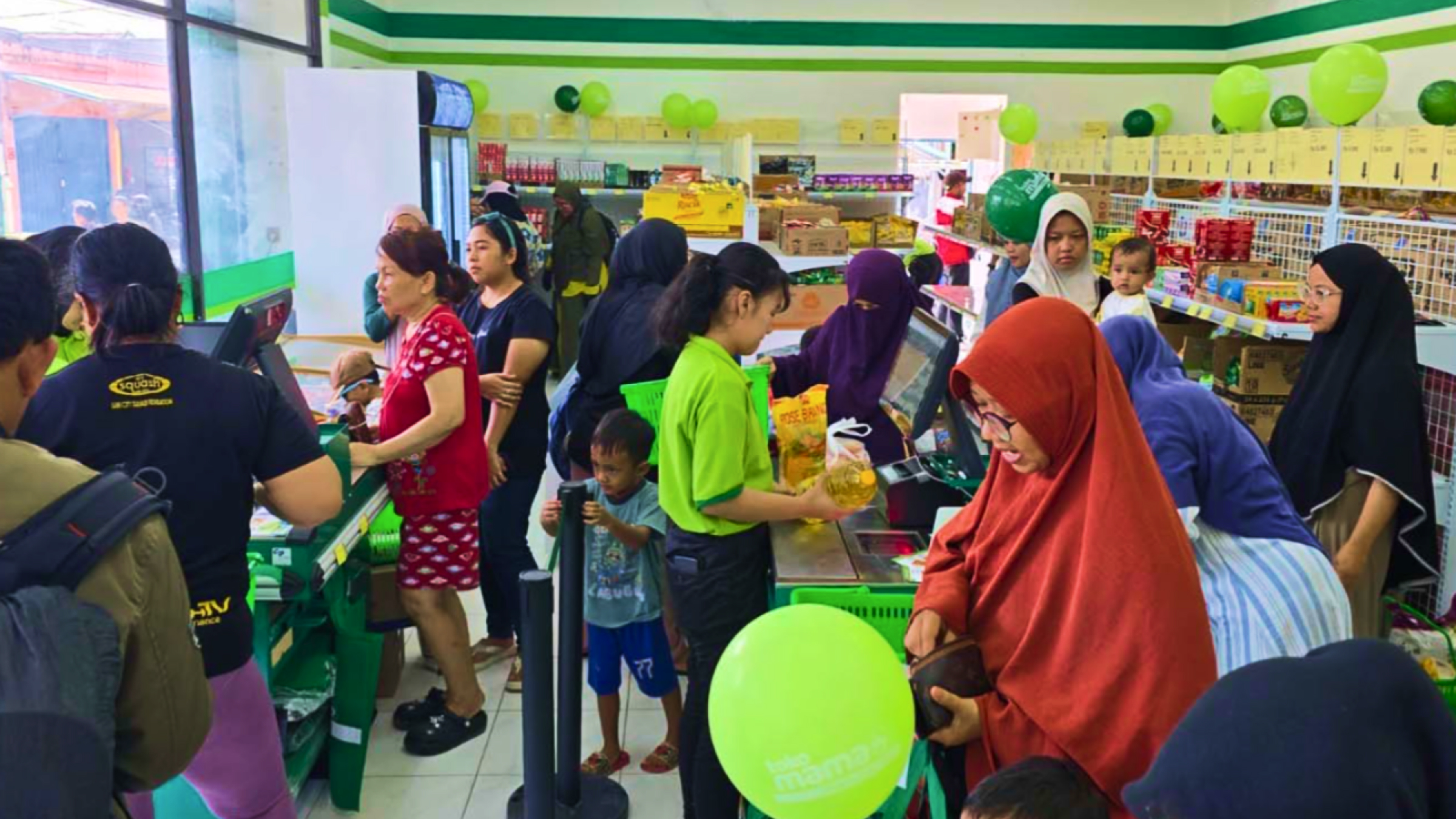 A busy Toko Mama convenience store with a cashier working the checkout line under high foot traffic